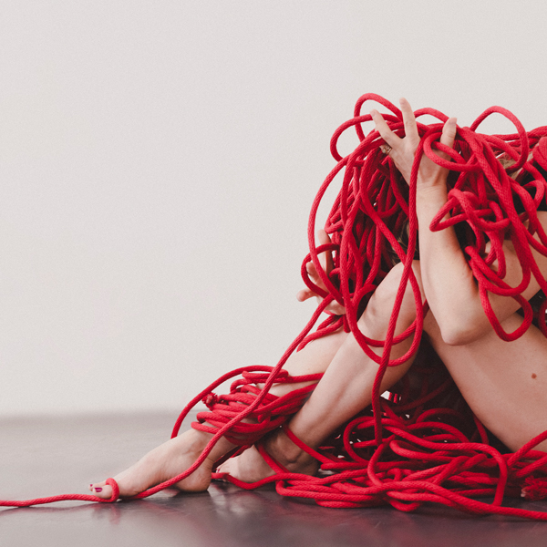 Dancer arms and legs shown amongst red rope